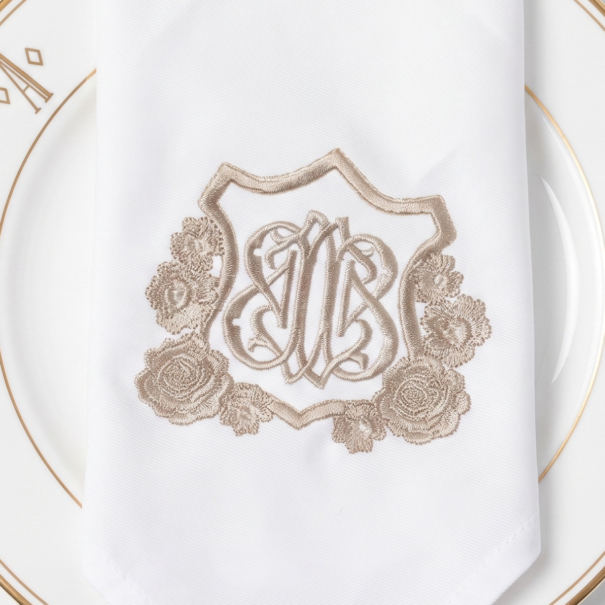 White napkin with monogram on a gold-rimmed plate